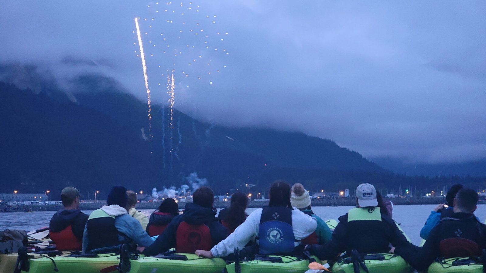 a group of people sitting in front of a body of water