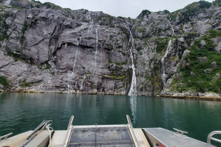 a boat that is sitting on a rock next to a body of water