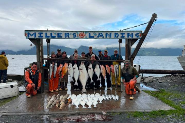 People posing with caught fish on a pier under 'Miller's Landing' sign.
