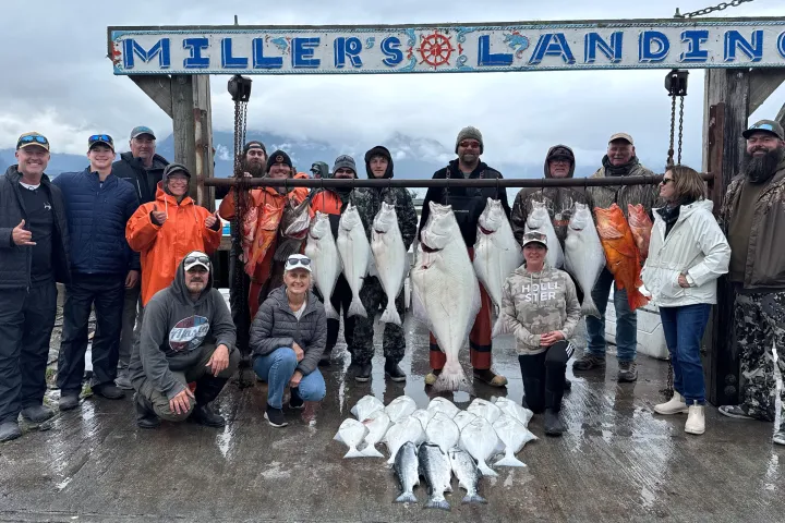 Group posing with caught fish hanging at Miller’s Landing sign.