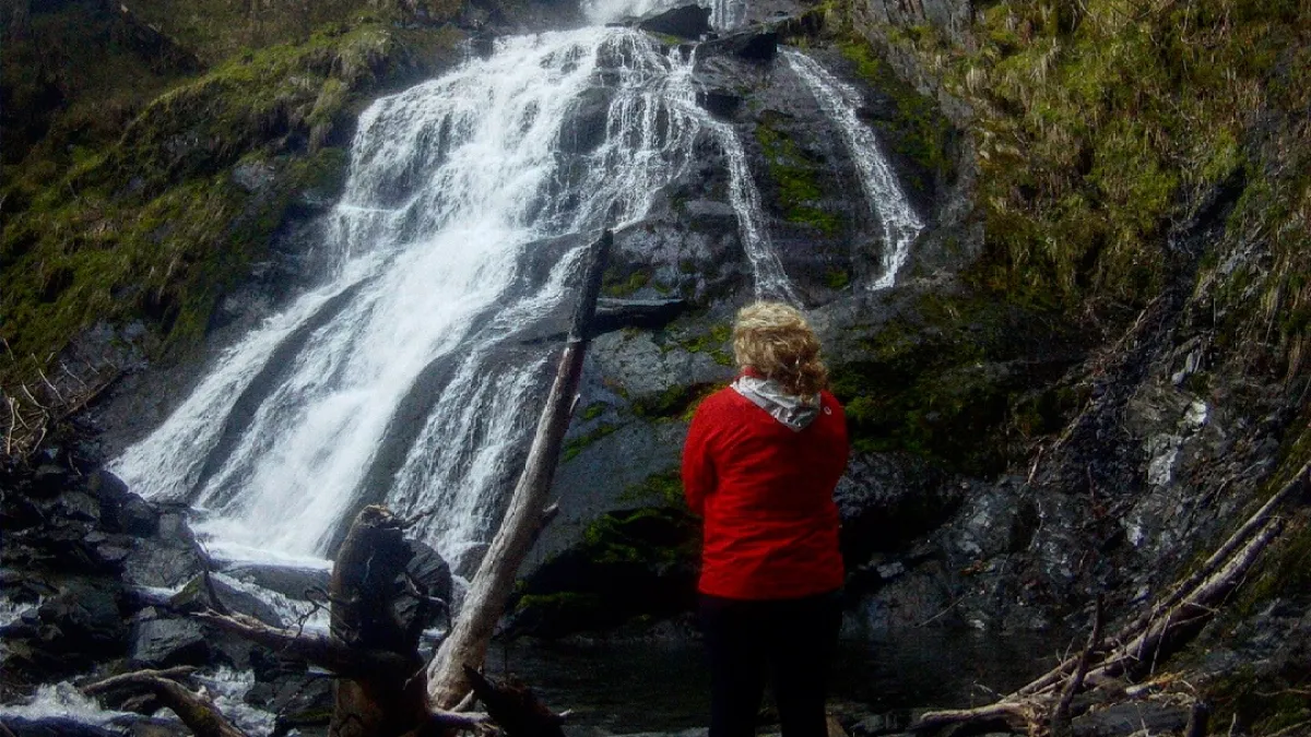 a man standing next to a waterfall