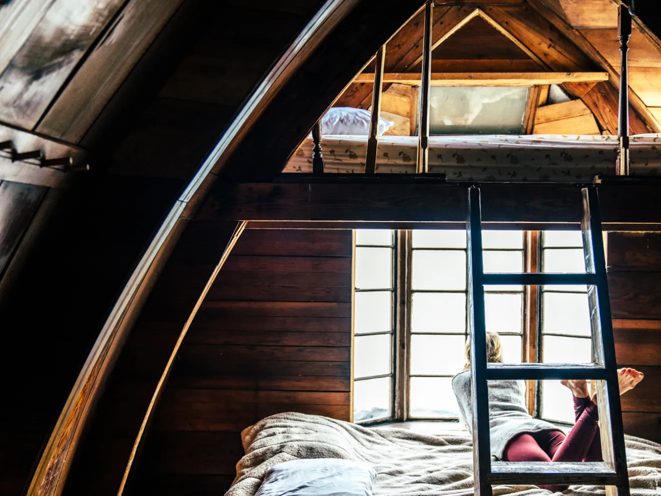 Girl laying in window of Seaside Camping Cabin and looking out at the baySeaside Beach Seward Alaska Kayaking Fishing Lodging Camping Guided Trips