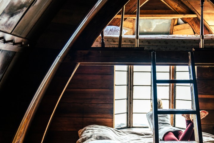 Girl laying in window of Seaside Camping Cabin and looking out at the baySeaside Beach Seward Alaska Kayaking Fishing Lodging Camping Guided Trips