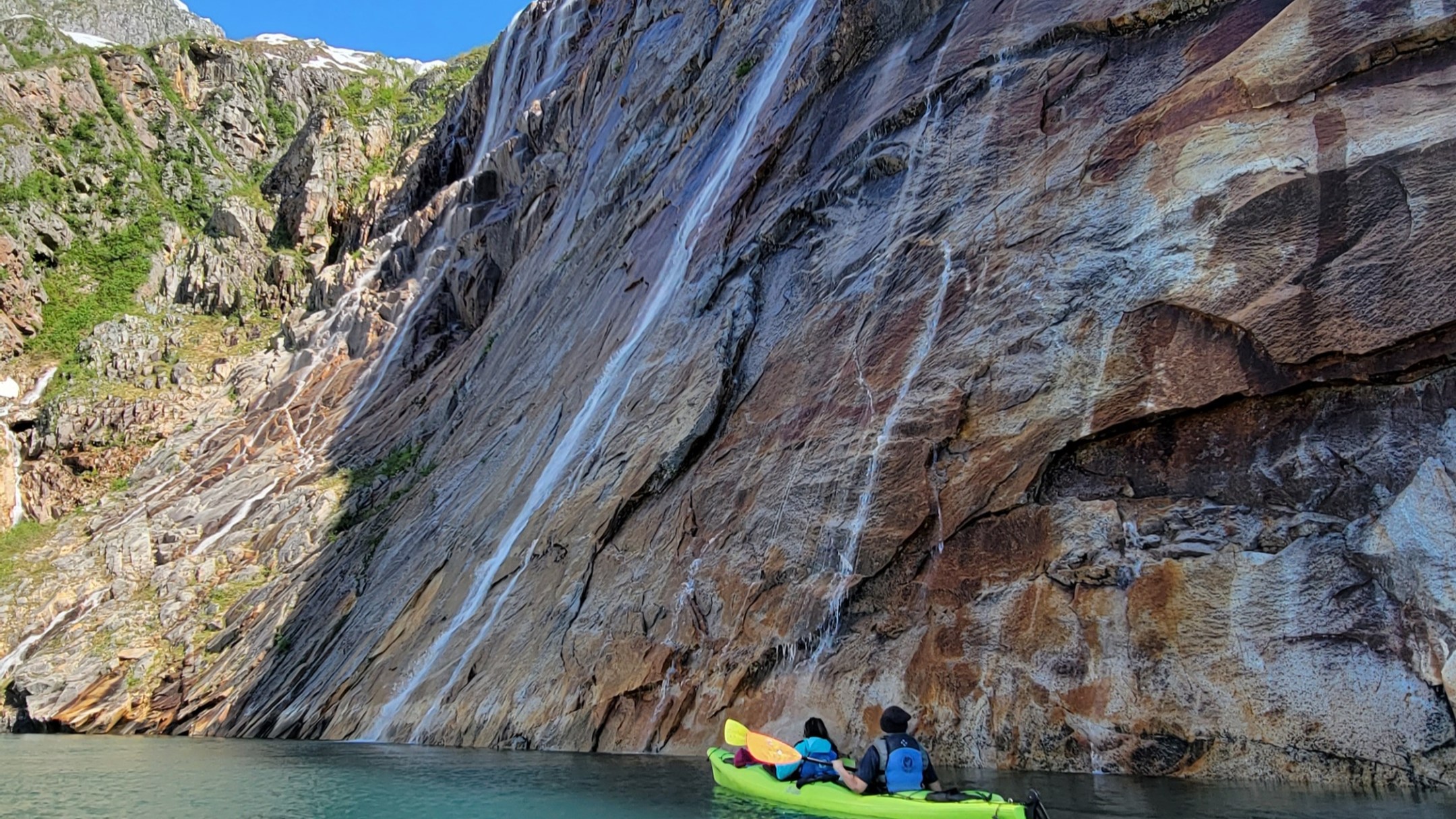 a group of people swimming in the water with a mountain in the background