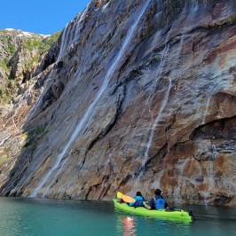 a group of people swimming in the water with a mountain in the background