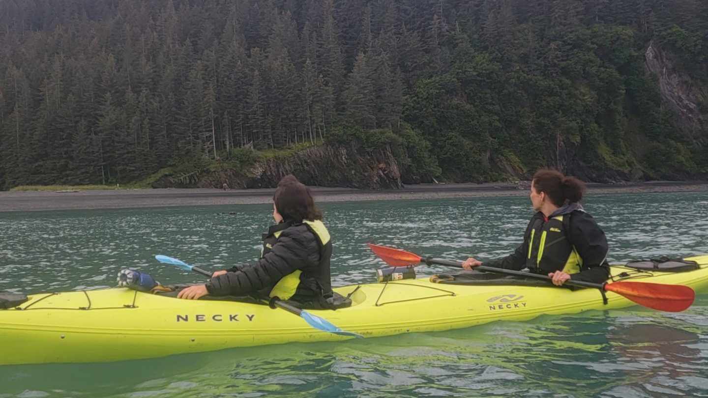 a man in a green boat on a body of water