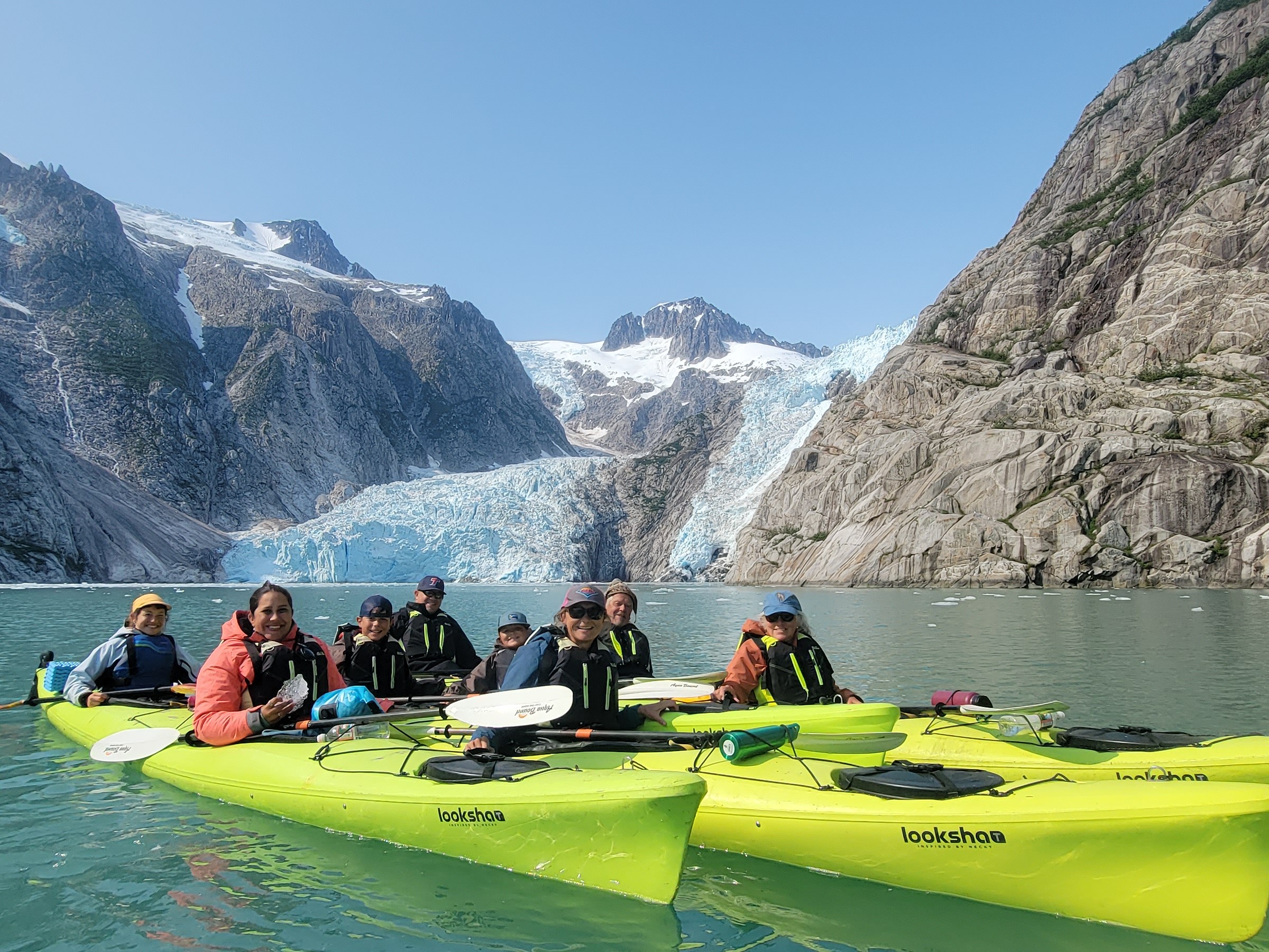 a group of people riding on the back of a boat in the water