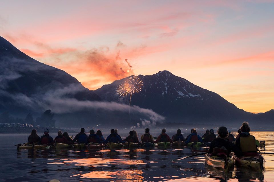 a group of people standing in front of a sunset