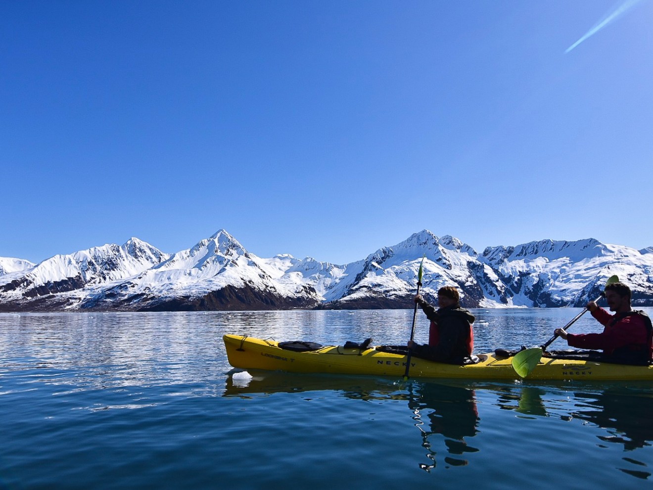 Kayaking on the open water with snowcapped mountains in the background