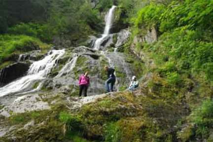 a group of people standing next to a waterfall