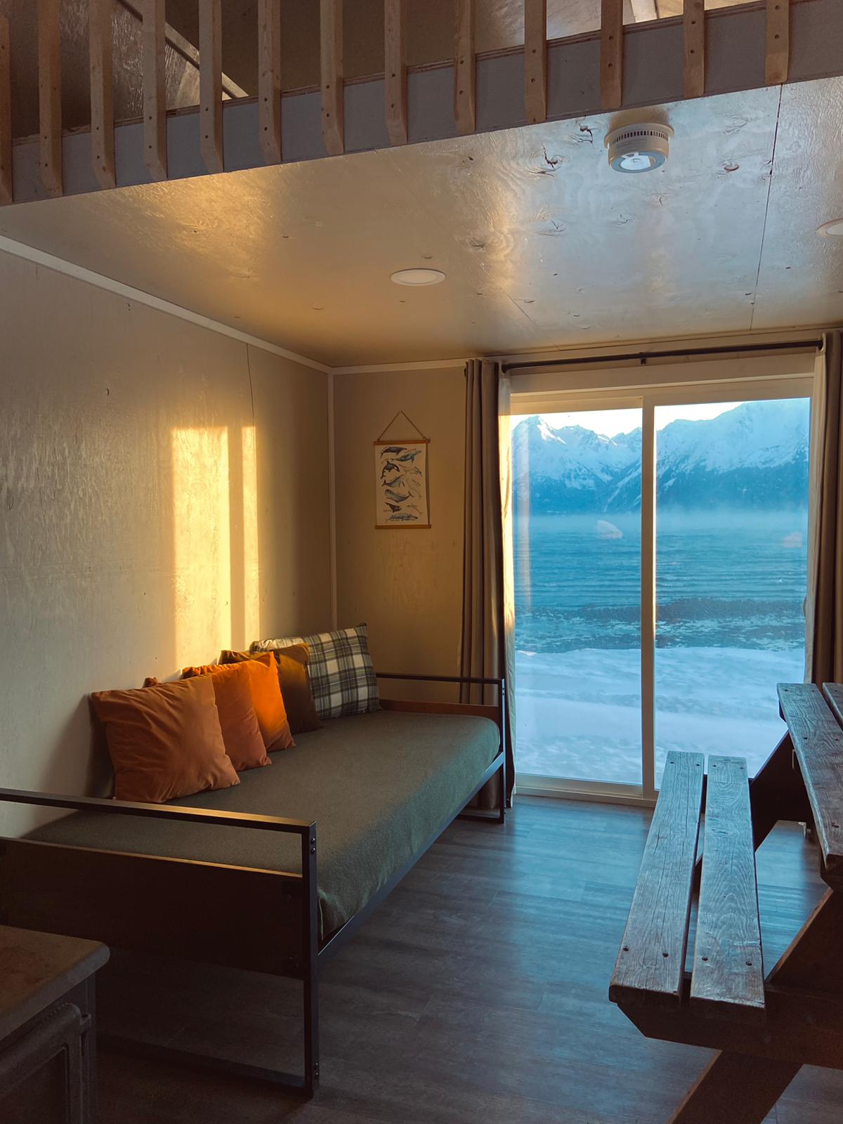 interior Beachfront Millers Landing cabin with bed, picnic table, and sliding door facing the bayMillers Landing Seward Alaska Beach Seaside