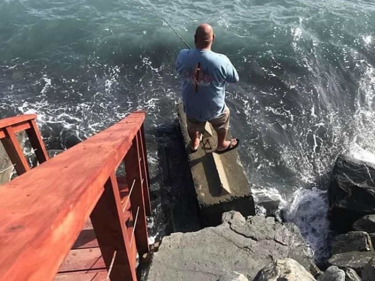 a man fishing from the rocks of Oceanfront Inn
