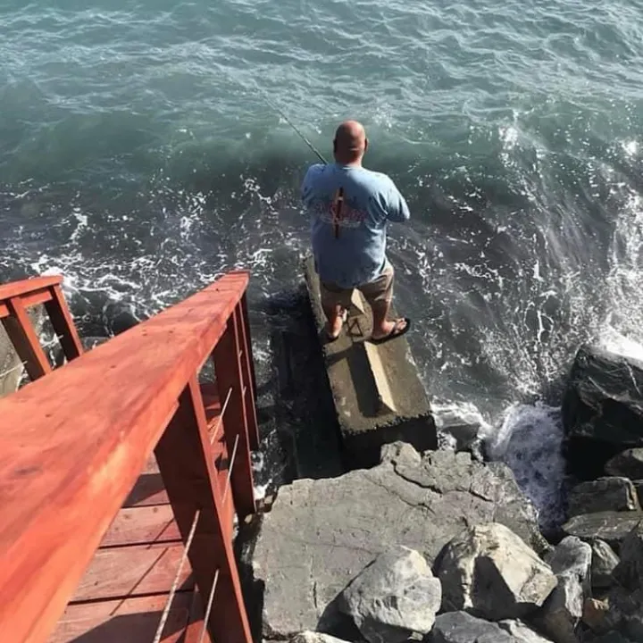a man fishing from the rocks of Oceanfront Inn