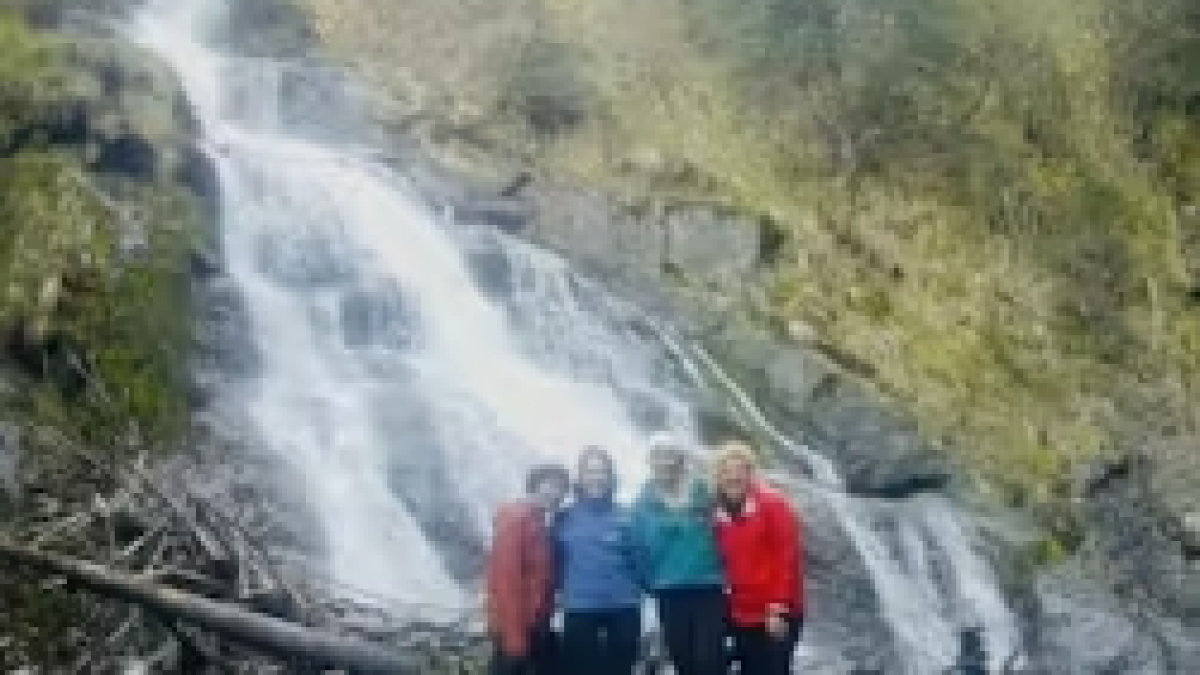 a group of people standing next to a waterfall