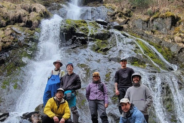 a group of people standing next to a waterfall