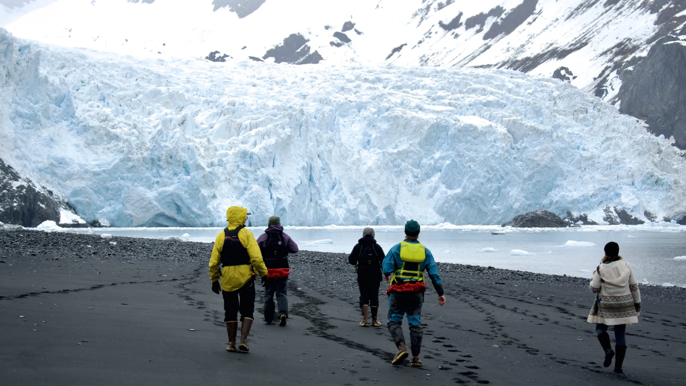 a group of people walking across a snow covered mountain