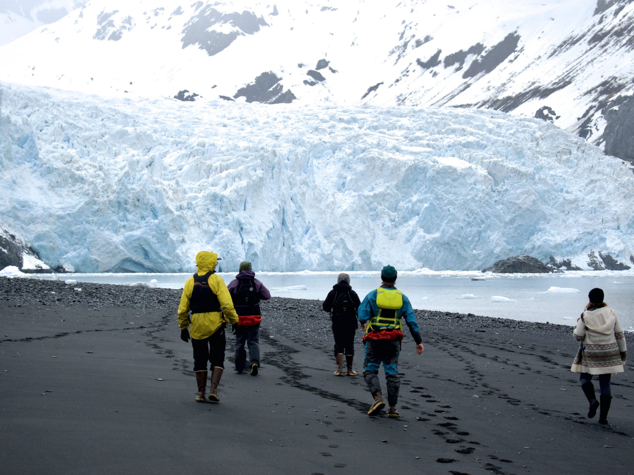 a group of people walking across a snow covered mountain