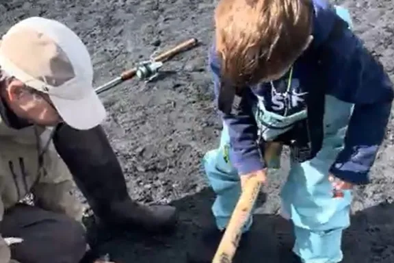 a kid using the fish bat after catching a salmon
