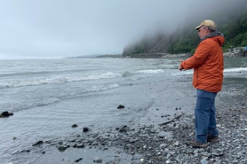 a man standing on a beach fishing for salmon