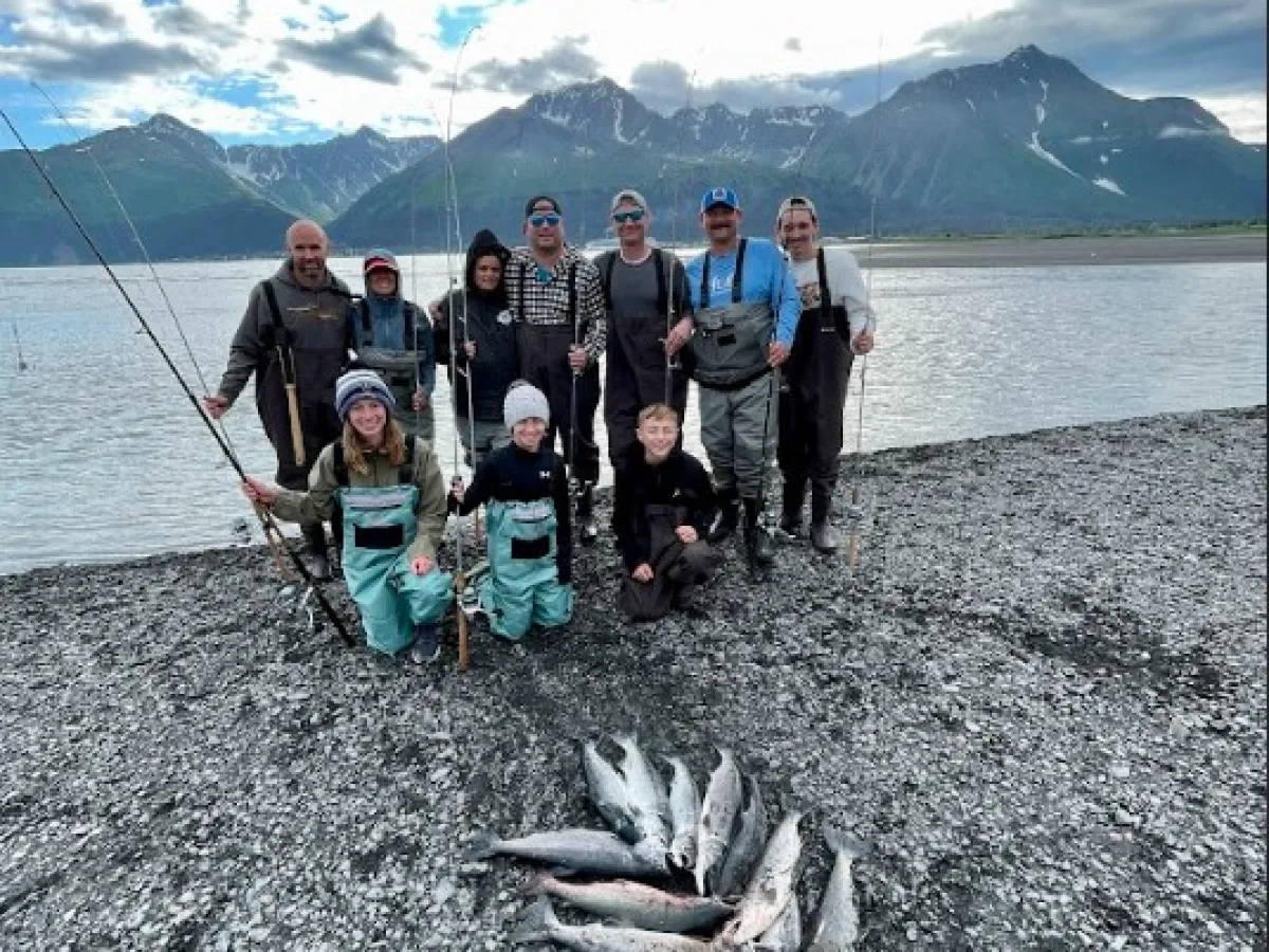 a group of people standing on the beach with al the salmons caught of the day