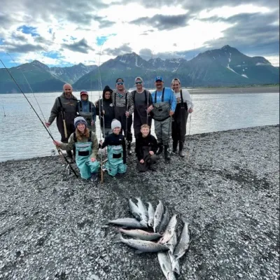 a group of people standing on the beach with al the salmons caught of the day
