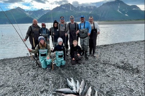 a group of people standing on the beach with al the salmons caught of the day