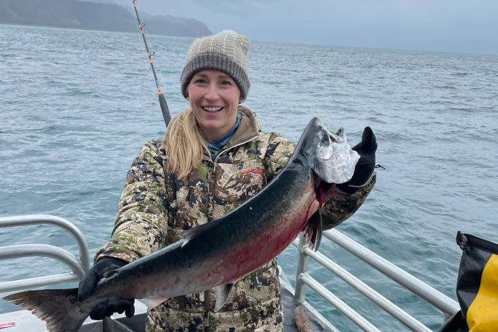 a man holding a fish on a boat in a body of water