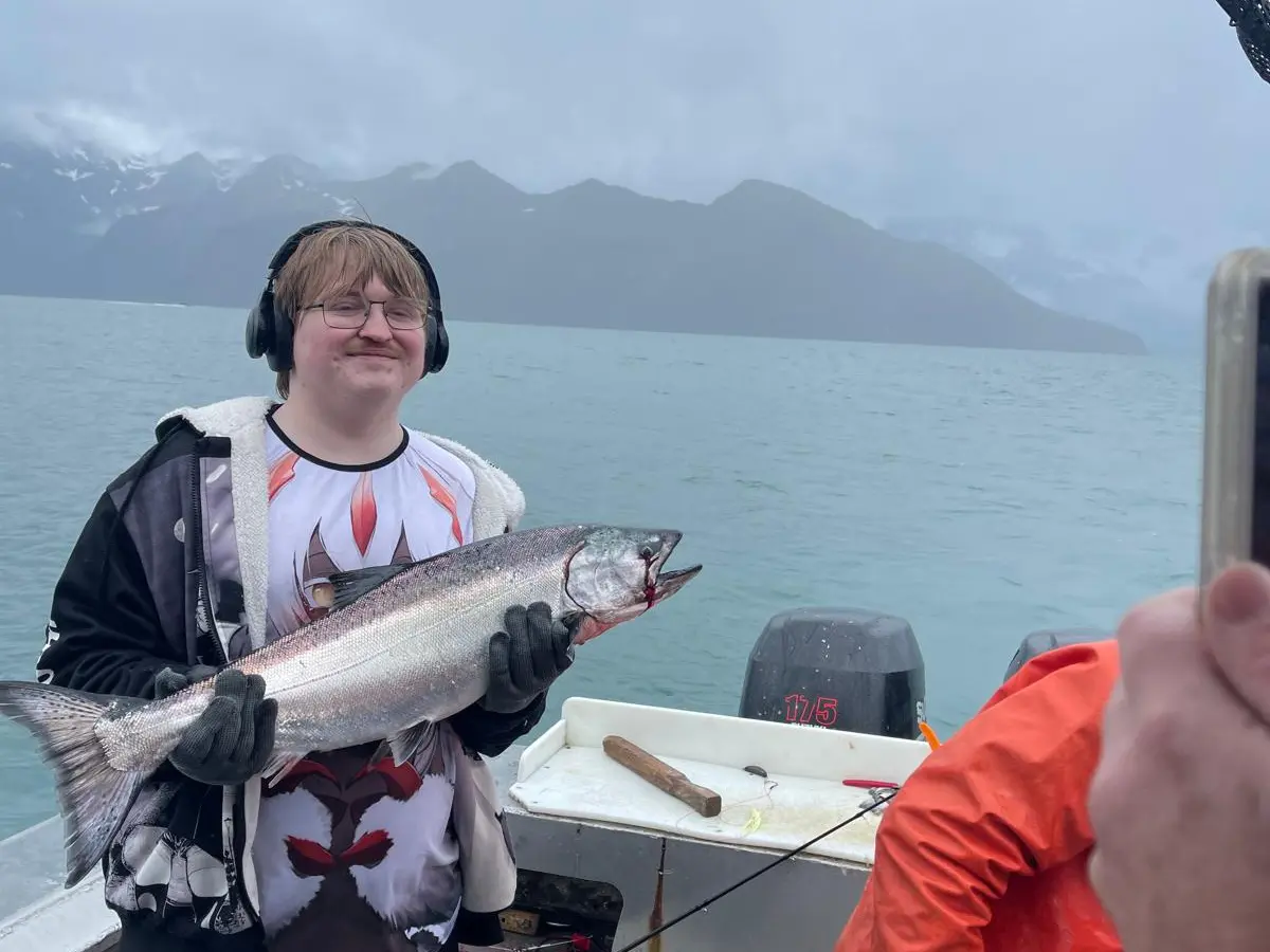 a man holding a fish on a boat in a body of water
