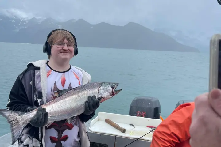 a man holding a fish on a boat in a body of water