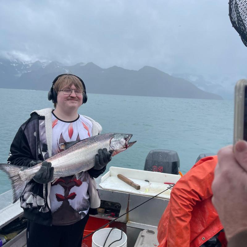 a man holding a fish on a boat in a body of water