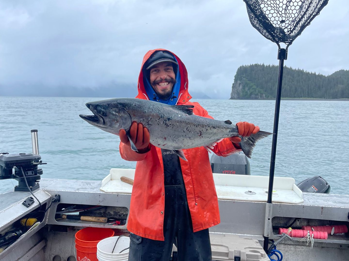 a person holding a King Salmon fish on a boat in the water