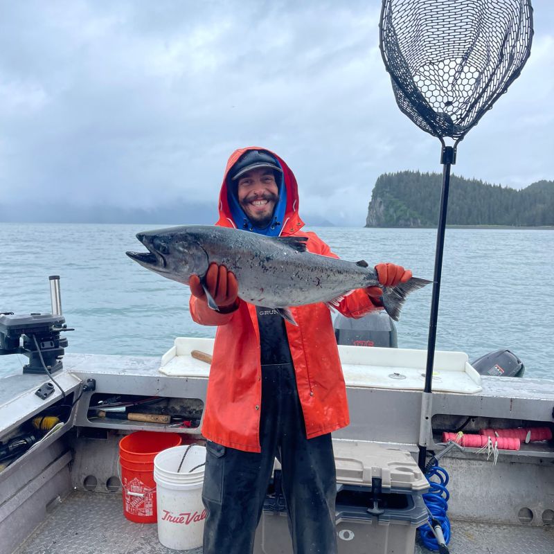 a person holding a King Salmon fish on a boat in the water
