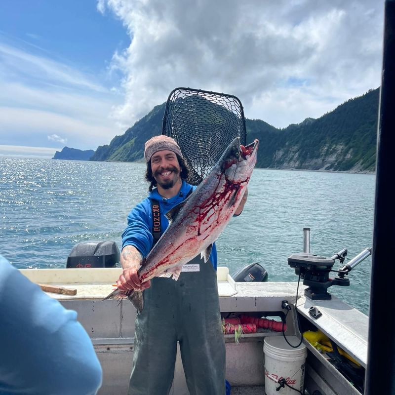 a person standing in front of a boat next to a body of water