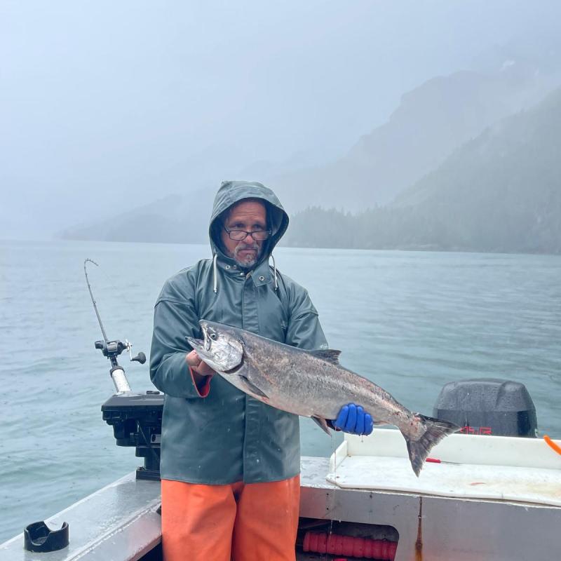 a man holding a fish on a boat in the water