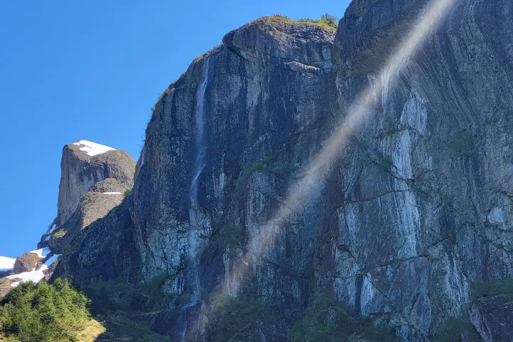 a waterfall with trees on the side of a mountain