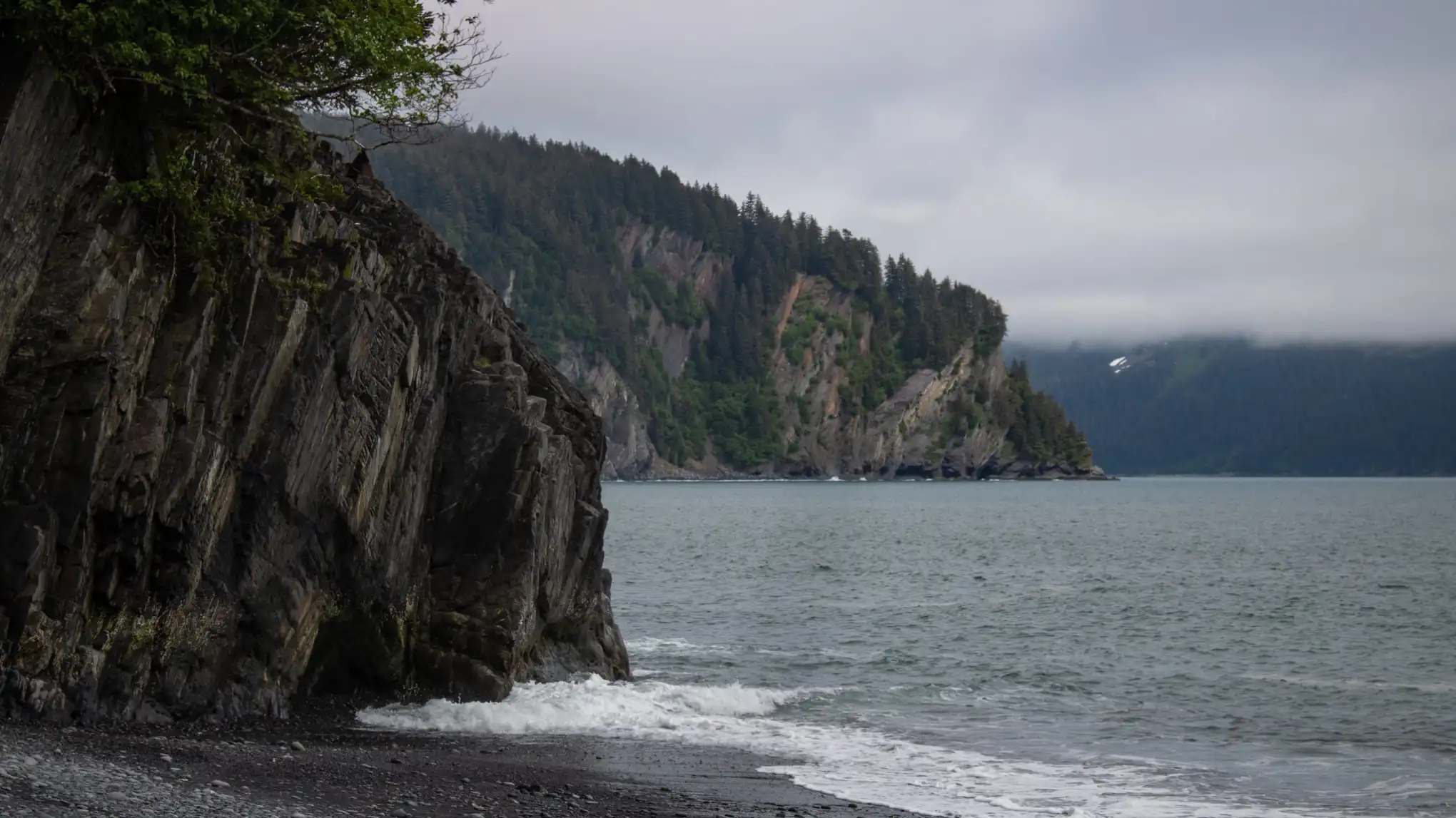 Seward alaska beach Caines heada body of water with a mountain in the background