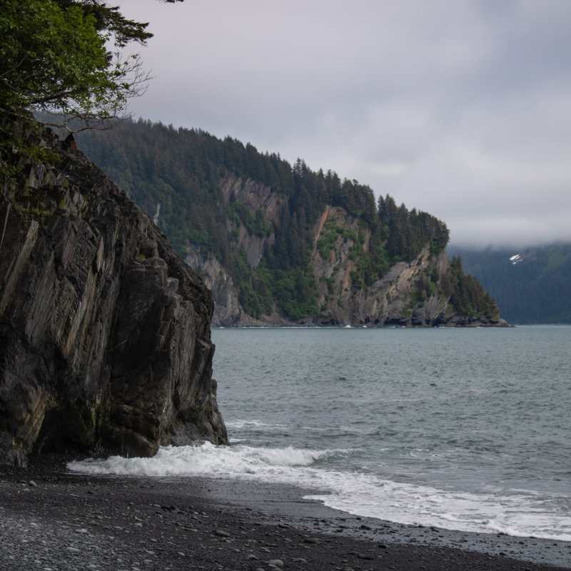 Seward alaska beach Caines heada body of water with a mountain in the background
