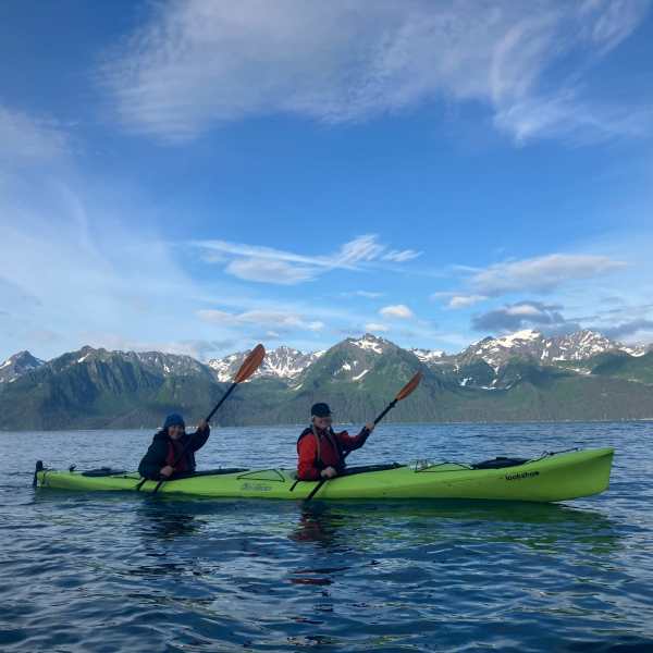 a group of people riding on the back of a boat in the water