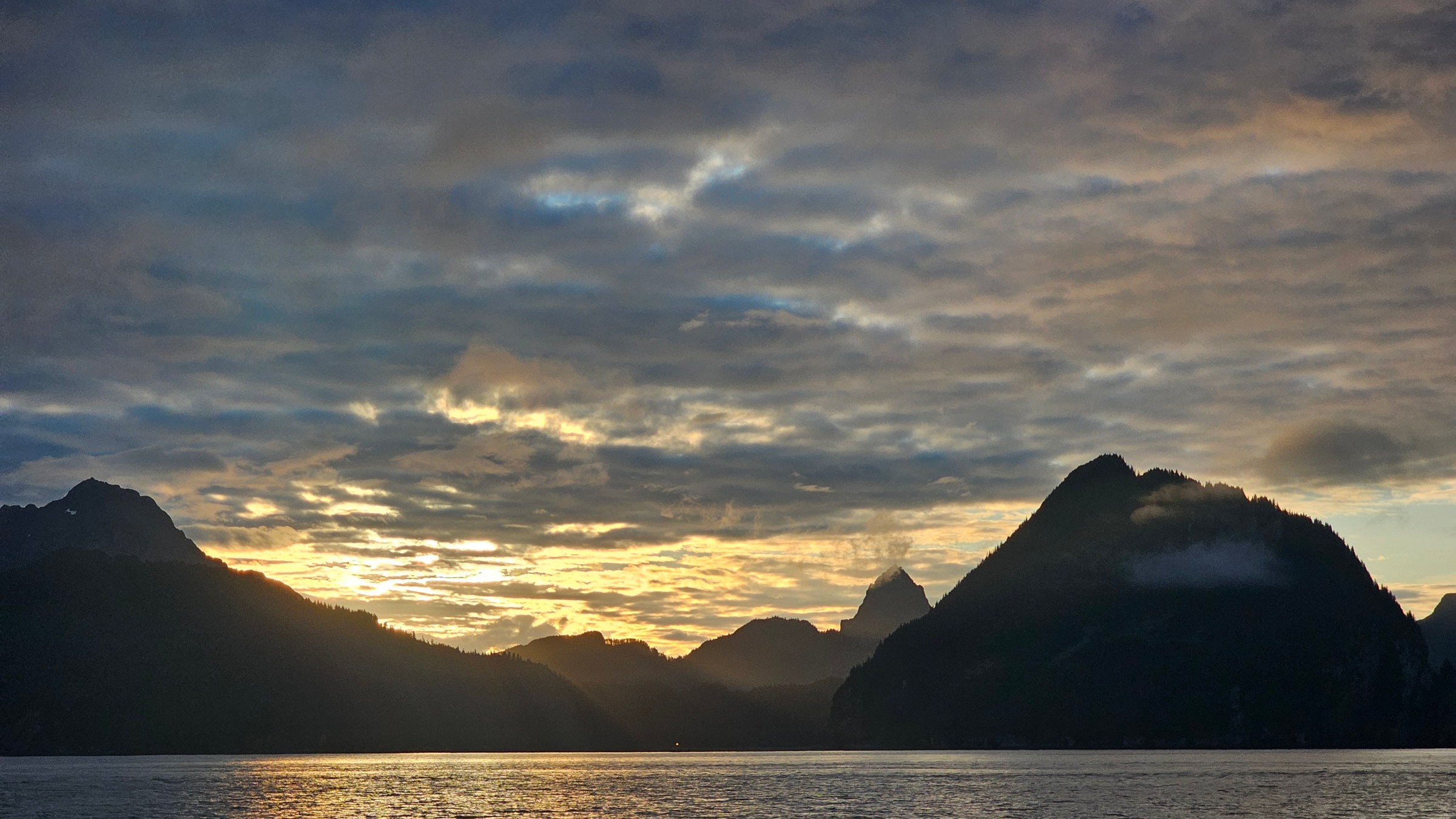 a sunset over the resurrection bay waters with the mountains in the background