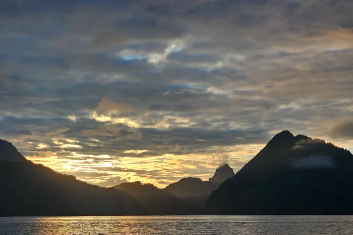 a sunset over the resurrection bay waters with the mountains in the background