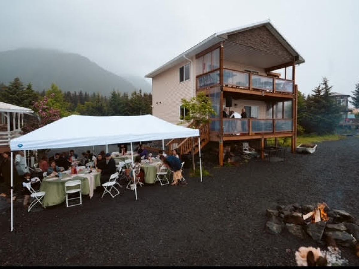 a group of people sitting at a table in front of a house