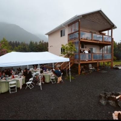 a group of people sitting at a table in front of a house