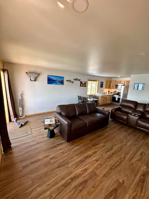 Living room with brown sofas, wooden floor, and fish-themed wall decor.
