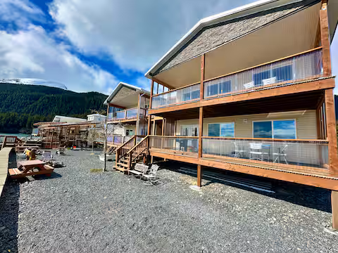 Two-story cabins with balconies overlooking a gravel patio and mountain background.