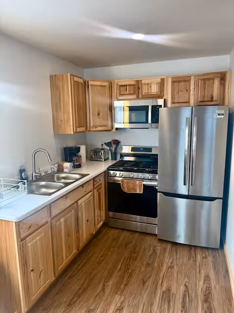 Wooden kitchen with stainless appliances and dual sinks.