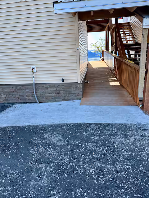 Wooden ramp leading to house entrance with stairs nearby.