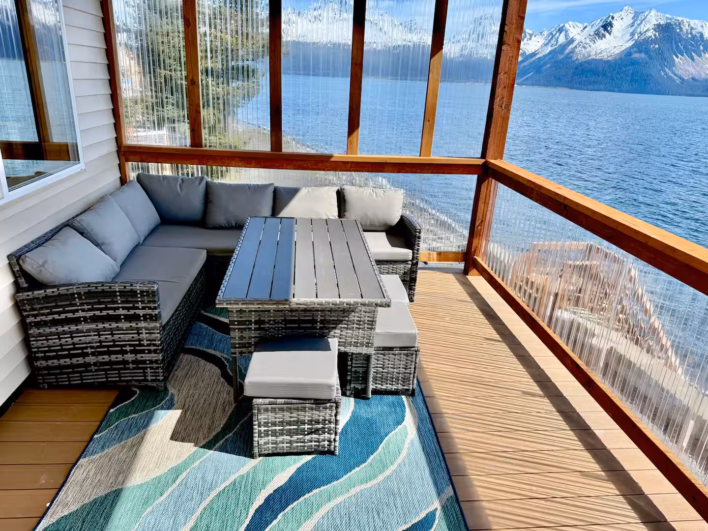 Patio with gray couch, table, and mountain lake view.