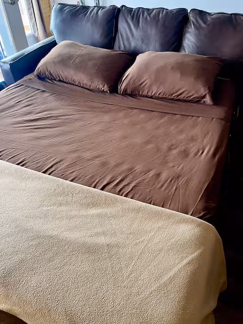 Brown bed with pillows and beige blanket in cozy room.