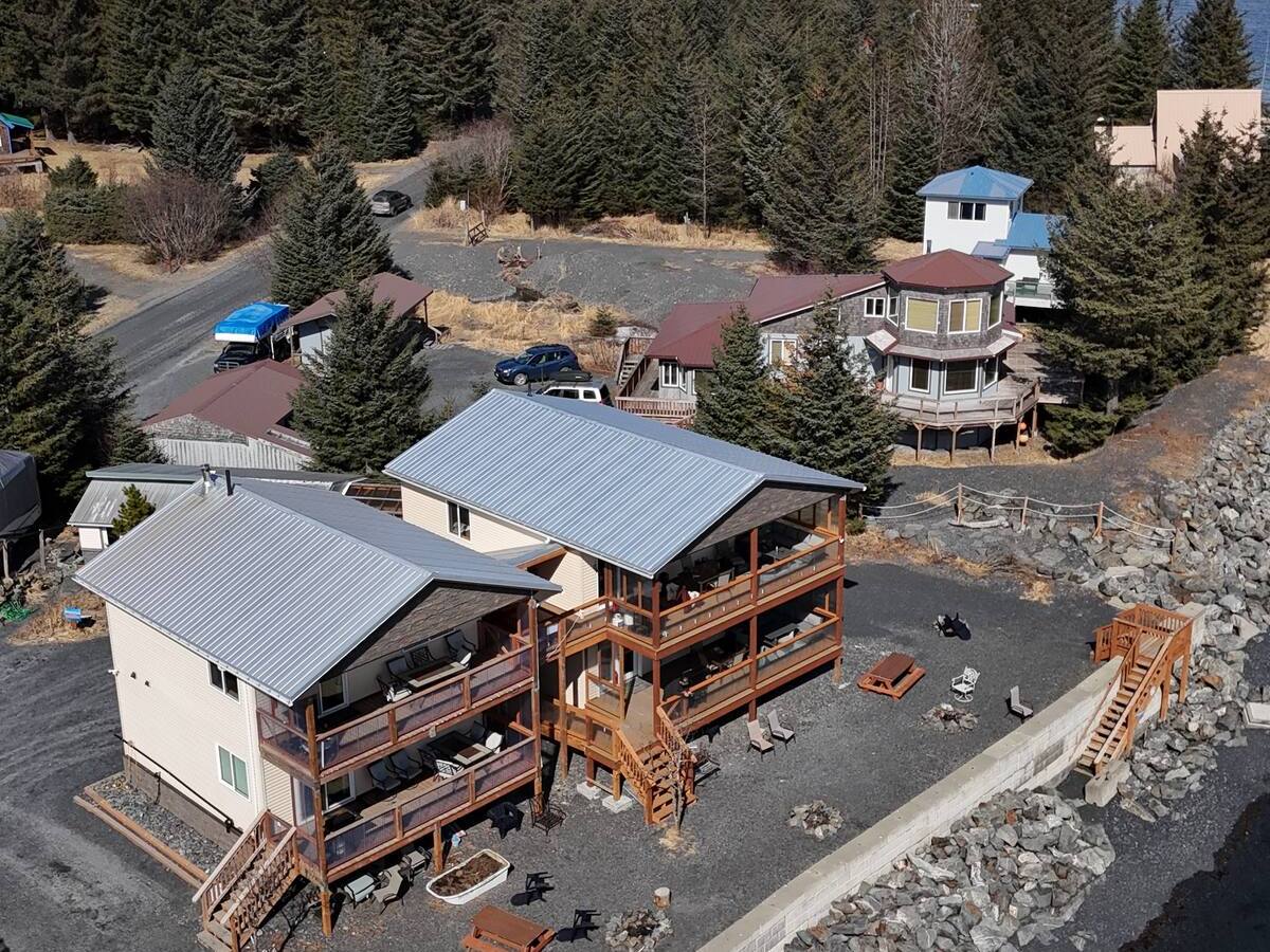 Coastal cabins with snowy mountains and forest in the background.