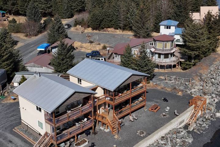 Coastal cabins with snowy mountains and forest in the background.